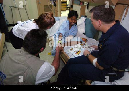 LE quarterback DES US Navy New York Giants Kurt Warner, au centre, et sa femme Brenda Sue visitent un patient d'amputé indonésien de 15 ans qui apprend à lire ses premiers mots en anglais Banque D'Images