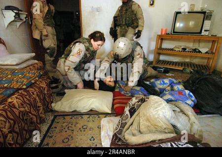 LES soldats DE l'armée AMÉRICAINE de la marine AMÉRICAINE affectés à l'équipe de combat de 2nd Brigade (BCT), 10th Mountain Division, aident une femme irakienne locale qui s'est évanouie alors que le BCT de 2nd procède à une fouille de son domicile pendant une Banque D'Images