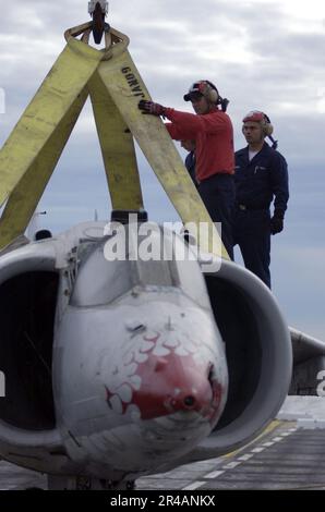 LES contraintes de Boatswain de L'AVIATION DE LA MARINE AMÉRICAINE travaillent ensemble sur un avion d'entraînement de Harrier AV-8A, tandis qu'un palan de grue est attaché à l'avion pendant les exercices d'entraînement sur le pont de vol à bord de l'assaul amphibie Banque D'Images