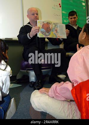 US Navy Hospital Corpsman 1st Class attribué au navire de transport amphibie USS Dubuque (LPD 8), montre des élèves de deuxième année à la Mesa Dale Elementary School à San Diego, en Californie, une page de a b Banque D'Images