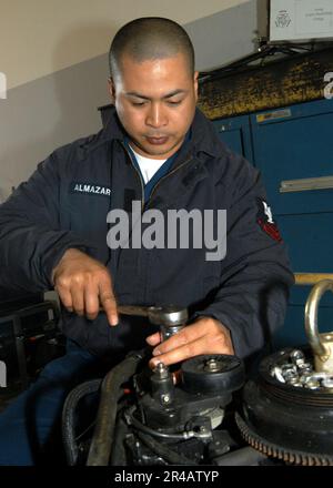 US Navy Engineman classe 2nd retire un alternateur d'un moteur hors-bord de bateau de sécurité portuaire à bord des États-Unis Activités de la flotte Sasebo, Japon. Banque D'Images