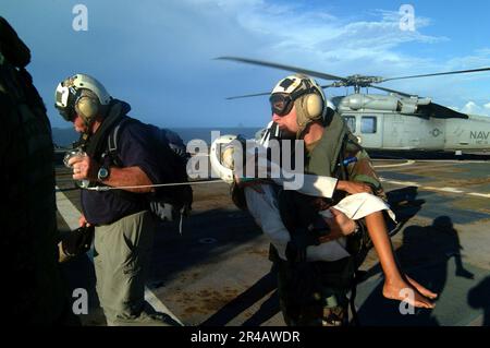 SOUS-ministre gauche de LA Marine AMÉRICAINE, à la retraite, il dirige le chef de l'hôpital Corpsman, alors qu'il transporte un enfant indonésien provenant d'un hélicoptère MH-60s Seahawk pour être traité médicalement. Banque D'Images