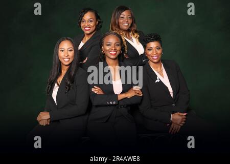 Un groupe de femmes d'affaires afro-américaines qui se posent sur un fond sombre Banque D'Images