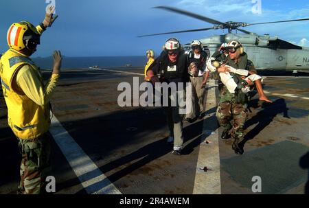 SOUS-ministre de la Marine AMÉRICAINE à gauche, dirige le chef de l'hôpital Corpsman, alors qu'il transporte un enfant indonésien provenant d'un hélicoptère MH-60s Seahawk. Banque D'Images