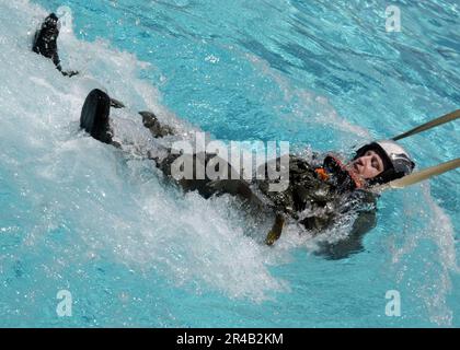 US Navy Un étudiant participant au cours de recyclage sur la survie de l'eau au centre d'entraînement de survie de l'aviation, Marine corps Air Station Miramar, est traîné avec une poulie dans une piscine. Banque D'Images