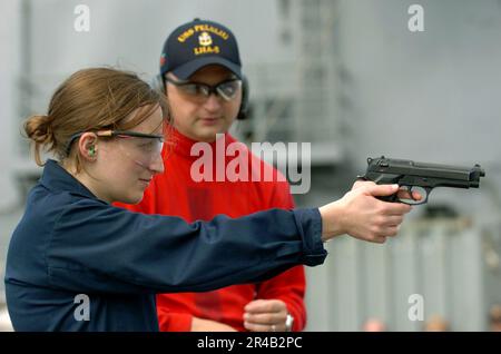 Le compagnon du chef DE la marine AMÉRICAINE Gunner instruit Ens. sur la bonne technique de tir d'un pistolet 9mm pendant une qualification d'armes de feu vivantes. Banque D'Images