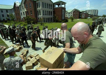 US Navy U.S. Le sergent d'état-major du corps maritime Foreground et le sergent Gunnery donnent des repas préemballés aux étudiants de la Marine alors qu'ils quittent leur caserne et s'alignent pour évacuer la base aérienne navale (NA Banque D'Images