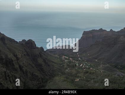 Vue aérienne vers la vallée du village de Taguluche avec de petites maisons, des falaises abruptes et l'océan atlantique, point de vue Mirador Ermita del Santo, Arure Banque D'Images