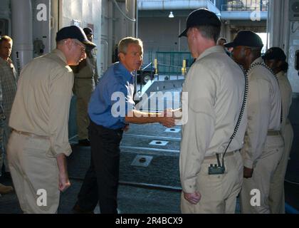 LE président DE la Marine AMÉRICAINE George W. Bush s'arrête pour serrer la main du personnel de la Marine qui se tient à des montres de quai avant de quitter le navire d'assaut amphibie USS Iwo Jima (LHD 7). Banque D'Images