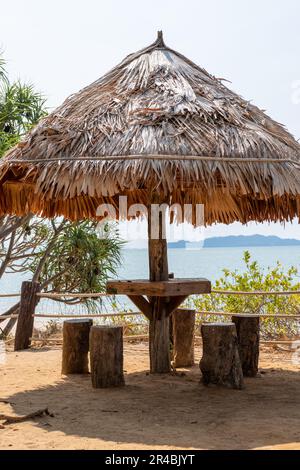 Assise sous un abri de cabane en bois, situé au bord de la mer. Banque D'Images