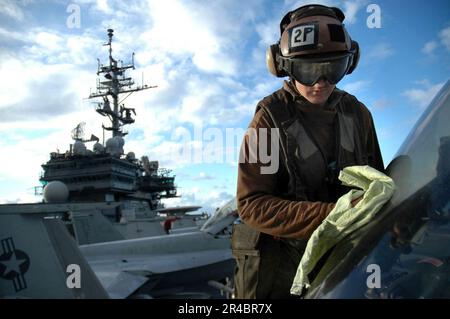 US Navy Aviation classe Machinist's Mate 3rd nettoie la voûte d'un F-A-18E Super Hornet en préparation pour les opérations de vol sur le pont de vol du transporteur aérien conventionnel US. Banque D'Images