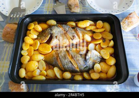 Dorade rôtie avec pommes de terre et sauce sur la table Banque D'Images