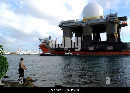 MARINE AMÉRICAINE Un pêcheur regarde comme le navire de levage lourd MV Blue Marlin entre dans Pearl Harbor, Hawaï, avec le radar X-Band basé sur la mer. Banque D'Images