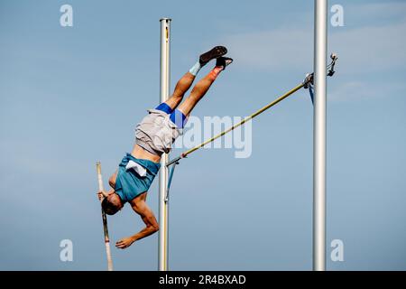 un athlète masculin sautant la voûte du mât lors des championnats d'athlétisme d'été sur fond bleu ciel Banque D'Images