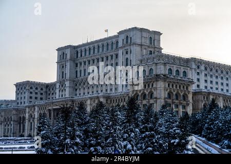 Une scène hivernale pittoresque avec l'emblématique Palais du Parlement de Roumanie, entouré de grands sapins et pins Banque D'Images
