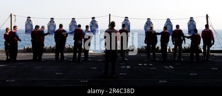 LES marins DE la Marine AMÉRICAINE se préparent à tirer 9mm pistolets Beretta tandis que les observateurs de sécurité indiquent une ligne de tir claire lors d'un exercice de qualification des armes légères sur un ascenseur d'avion à bord du porte-avions de la classe Nimitz. Banque D'Images