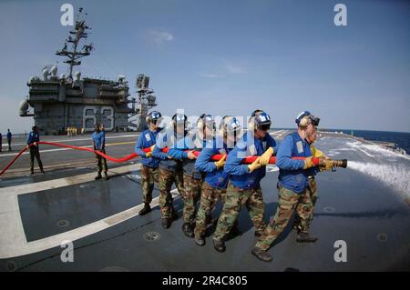 Le personnel DU département DE l'Air DE LA Marine AMÉRICAINE lave de la mousse à formation de film aqueuse (AFFF) hors du plateau de vol à bord du USS Kitty Hawk (CV 63) à alimentation conventionnelle tout en participant aux exercices de lutte contre l'incendie du navire. Banque D'Images