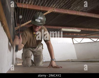 US Navy U.S. Navy Utiliesman 2nd Class affecté au Naval Mobile Construction Battalion Seven (NMCB-7), marteaux la dernière section de contreplaqué de plafond. Banque D'Images