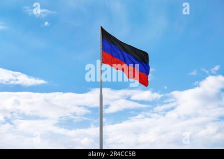 Le drapeau de la République populaire des Donets (DPR ou DNR) autoproclamée agite devant le ciel bleu et les nuages Banque D'Images