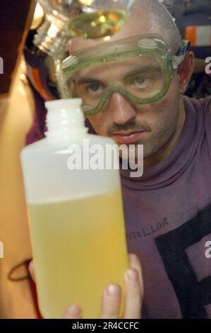 US Navy Aviation Boatswain's Mate Fuels Airman prépare un échantillon de carburant pour l'assurance qualité. Banque D'Images