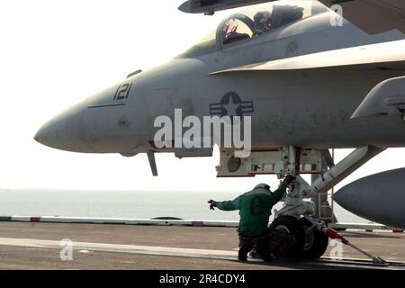 US Navy Un membre de l'équipage de plate-forme de vol signale de faire avancer la navette pour le lancement d'un F-A-18E Super Hornet affecté aux titreurs du Strike Fighter Squadron One Zero Five (VFA-105). Banque D'Images