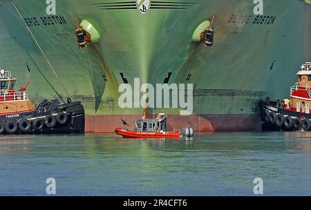 US Navy Un bateau de réponse de 25 pieds de la Garde côtière est flanqué de deux remorqueurs tandis que le pétrolier de gaz naturel liquide (GNL) Berge Boston est amarré à la jetée d'une installation de GNL à Boston. Banque D'Images