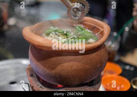 Jim Joom, style thaïlandais de hot pot du nord-est de la Thaïlande contient du porc, des légumes et des nouilles de verre dans un bol en argile Banque D'Images