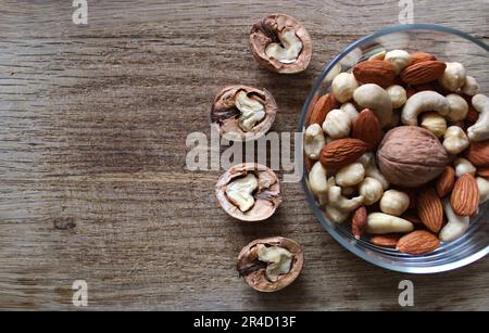 Variété de noix pelées dans un bol et quatre moitiés d'une noix sur un panneau en bois d'époque Banque D'Images