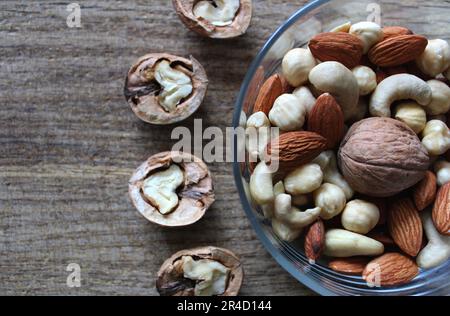 Noix mélange d'amandes, de noisettes et de noix de cajou dans une soucoupe en verre et noix de Grenoble divisées en deux Banque D'Images