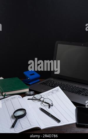 Bureau au bureau. Un stylo à bille reposant sur un tourillon. Documentation et ordinateur portable. Cadre vertical. Banque D'Images
