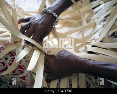 Les mains des femmes en gros plan à tisser quelque chose hors des feuilles de palmier Banque D'Images