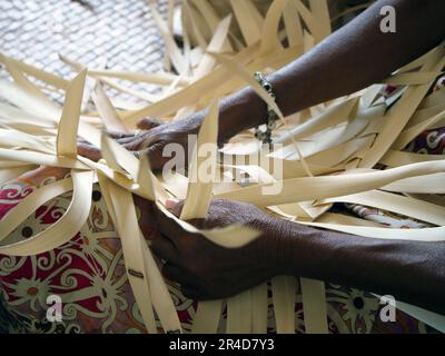Les mains des femmes en gros plan à tisser quelque chose hors des feuilles de palmier Banque D'Images