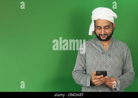 Indian Young Farmer faisant quelque chose avec les deux mains dans son écran mobile en écran vert, Copy Space Banque D'Images