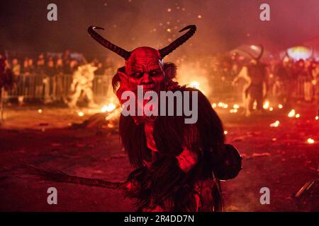 Un groupe de personnes debout devant un feu torant, avec certains d'entre eux donnant des costumes démoniaques Banque D'Images