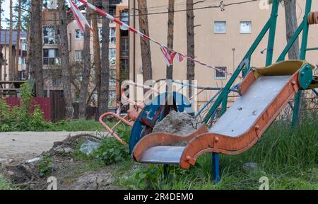 Guerre en Ukraine. Terrain de jeu détruit dans le centre-ville. Les ruines d'un immeuble de grande hauteur détruit par un missile russe un an après l'occupation. Banque D'Images