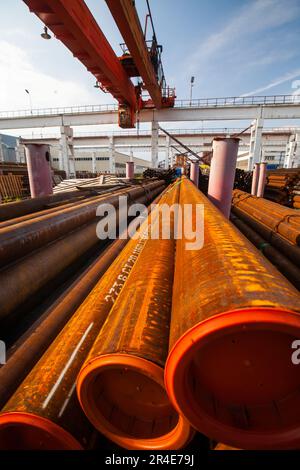 Tuyaux et tubes en acier rouillés en entrepôt extérieur. Pont roulant vers le haut. Ciel bleu Banque D'Images