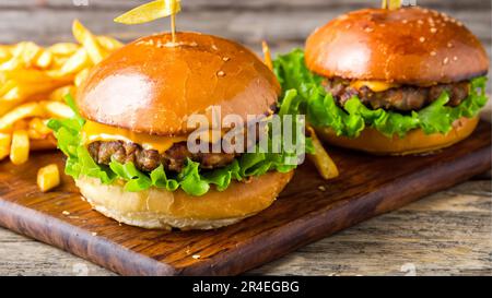 Hamburger savoureux avec frites sur une table en bois Banque D'Images