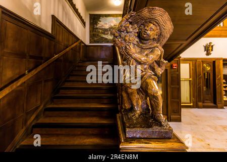 L'ancien Hôtel Münchnerhof à Dreifaltigkeitsgasse 3, Salzbourg, Autriche, avait 100 chambres accessibles par un escalier lambrissé de bois sombre, éclairé par un toit en verre et un énorme lustre en cristal. Vous pouvez encore y voir de nombreuses figures sculptées avec le motif Münchner Kindl Banque D'Images