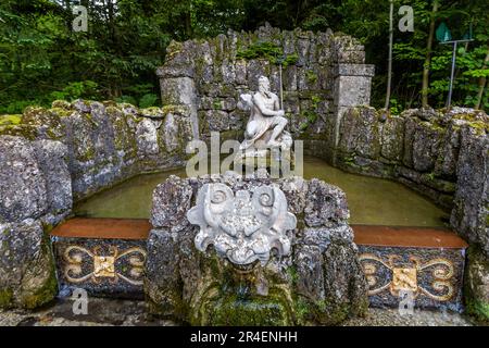 Fontaine de Neptune, qui est une statue du dieu Neptune assis sur un dauphin au Palais Hellbrunn à Salzbourg, en Autriche. Devant le morceau de roche se trouve un masque de marbre grotesque, de dont la bouche coule de l'eau Banque D'Images