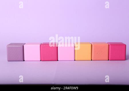 Videz les cubes colorés sur fond lilas, espace pour le design Banque D'Images
