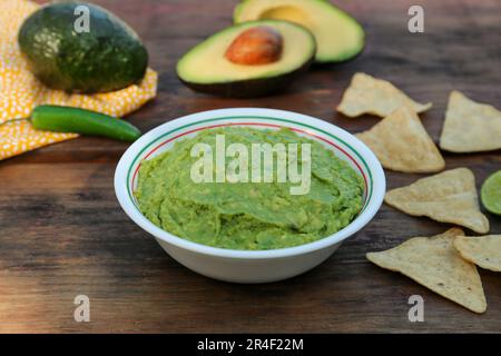 Délicieux guacamole fait d'avocats avec nachos sur table en bois Banque D'Images