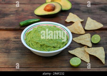 Délicieux guacamole fait d'avocats avec nachos sur table en bois Banque D'Images