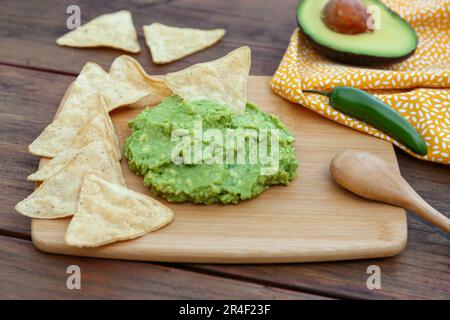 Délicieux guacamole fait d'avocats, de nachos et d'une cuillère sur une table en bois Banque D'Images