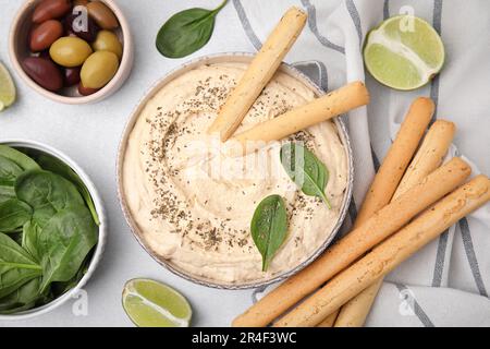 Délicieux houmous avec bâtonnets de grissini servis sur une table gris clair, ponté à plat Banque D'Images