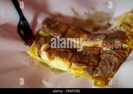 Roti à la banane et au chocolat en poudre, servi sur assiette Banque D'Images