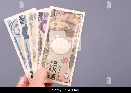 Argent japonais - yen dans la main sur fond gris. Banque D'Images