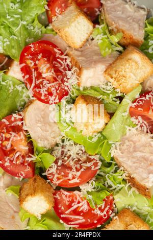 Salade de légumes avec poulet et fromage sur une table grise. Salade César dans une assiette grise. Banque D'Images