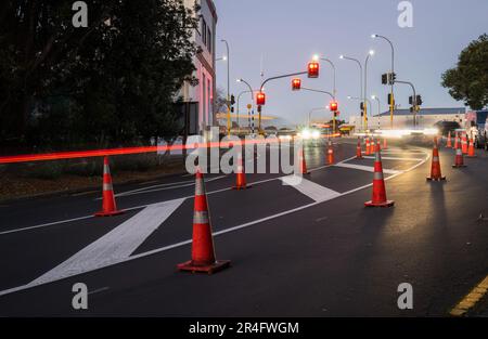 Des cônes de signalisation orange sont alignés sur la route. Les feux de signalisation de la voiture s'allument à l'intersection. Auckland. Banque D'Images