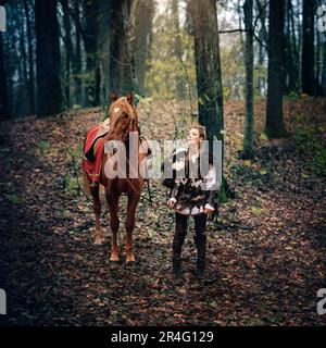 Guerriers sauvages : la femme du Nordic Viking Warrior et son Majestic Horse embrassent la forêt dans la reconstruction de la scène médiévale, mettant en valeur le traditionnel AT Banque D'Images