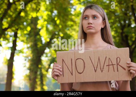 Triste femme tenant une affiche avec des mots No War dans le parc. Espace pour le texte Banque D'Images